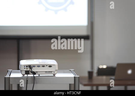 Projecteur multimédia blanc dans une salle de conférence avec écran de projection blured et chargée de 24 sur l'arrière-plan (réduit) Banque D'Images
