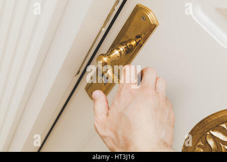 Main mâle blanc ouvre la porte en bois avec poignée d'or, la photo en gros plan avec selective focus Banque D'Images