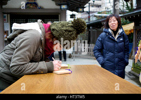 L'écriture des élèves sur une tablette comme prière mère les regarde. Sanctuaire Shinto Yushima Tenmangu, situé dans le quartier de Bunkyo, Tokyo Japon. Il s'agit d'un fav Banque D'Images