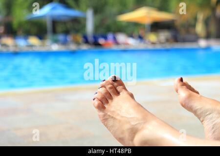 Pieds de femme floue avec piscine ensoleillée en arrière-plan Banque D'Images