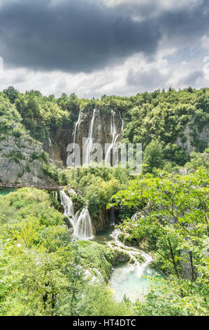 Les nuages de tempête survolez les nombreuses cascades et à des formations karstiques de la Croatie Le parc national des Lacs de Plitvice, tandis que les touristes pack les allées. Banque D'Images