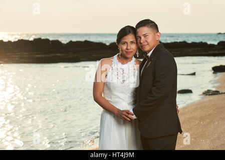 Portrait of young hispanic couple marié sur coucher soleil océan plage. Heureux époux et épouse latino Banque D'Images