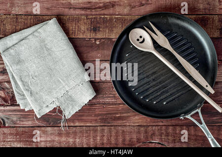 Gril et ustensiles de cuisine en bois sur une surface en bois brun, vue du dessus Banque D'Images