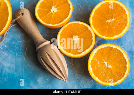 Juicy mûr oranges fraîches coupées en deux avec l'alésoir en bois sur fond de béton bleu, top view, Close up, copyspace Banque D'Images