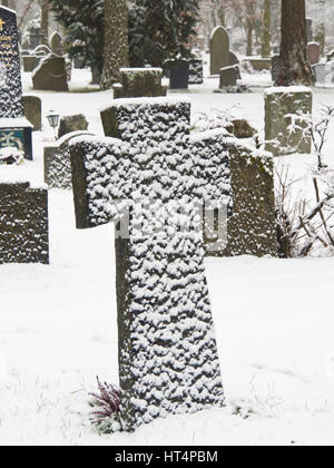 Croix de Pierre Pierre tombale dans un cimetière couvert de neige par le vent, Oslo Norvège Banque D'Images