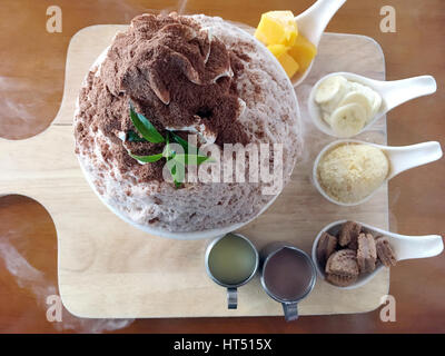 Bingsu dessert (Corée) glace laiteux finement moulu aromatisé avec le chocolat en poudre et garniture de fruits qui inclut la mangue, la banane et les cookies remplis de d Banque D'Images