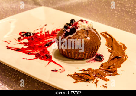 Muffin plaque de avec un brin de groseille rouge avec de la crème glacée à la menthe confiture et saupoudré de sucre en poudre. Gâteau au chocolat avec de la crème glacée, des fruits rouges et de menthe. Banque D'Images