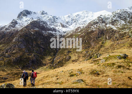 Les randonneurs randonnée dans le Cwm Idwal à snow-capped Y Garn en montagne montagnes de Snowdonia National Park. Ogwen, Gwynedd, au nord du Pays de Galles, Royaume-Uni, Angleterre Banque D'Images