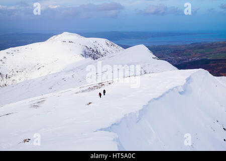 Vue depuis le nord de la montagne Y Garn Glyderau gamme dans les montagnes de Snowdonia National Park avec les randonneurs randonnées en hiver et de la neige au-delà de la côte. Pays de Galles UK Banque D'Images