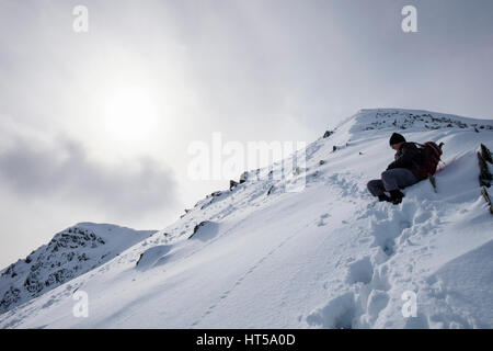 Vue d Y Garn pic de montagne à partir de la crête avec hiker resting in winter conditions de neige dans les montagnes de Snowdonia National Park. Pays de Galles, Royaume-Uni, Angleterre Banque D'Images