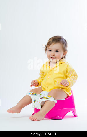 Little smiling girl sitting on un pot. Isolé sur fond blanc. Banque D'Images