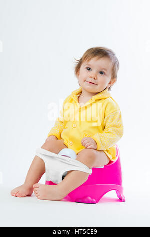 Little smiling girl sitting on un pot. Isolé sur fond blanc. Banque D'Images