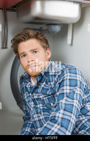 Les jeunes plumber repairing sink in kitchen Banque D'Images