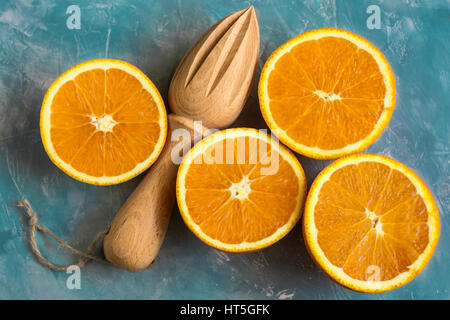 Composition de couleurs lumineuses oranges mûres coupées en deux avec l'alésoir en bois sur fond bleu, top view, Close up Banque D'Images