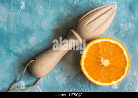 Mûrs juteux orange frais réduit de moitié avec l'alésoir en bois sur béton, fond bleu top vue, télévision lay, copyspace Banque D'Images