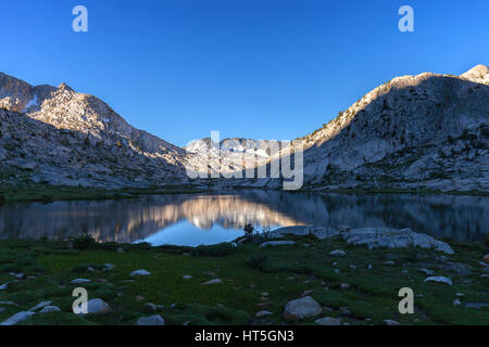 Première lumière du soleil du matin se déverse dans le lac l'évolution dans la Sierra Nevada sur la Pacific Crest Trail. Banque D'Images