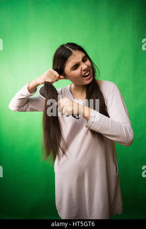 Teen girl in nuisette comb cheveux à fond chroma key vert Banque D'Images