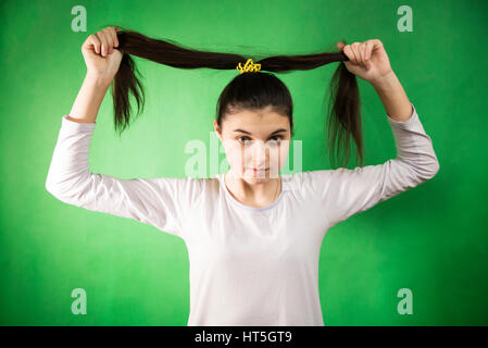 Teen girl in nuisette comb cheveux à fond chroma key vert Banque D'Images