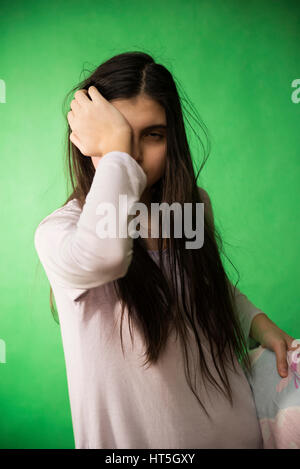 Fille dans sa nuisette veut dormir et se frotte les yeux sur un fond vert d'incrustation isolée Banque D'Images