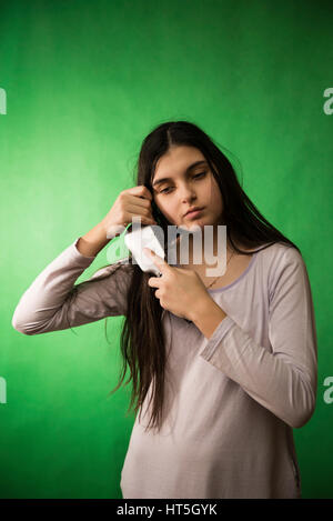 Teen girl in nuisette comb cheveux à fond chroma key vert Banque D'Images