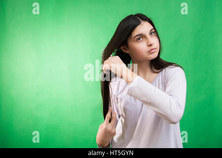 Teen girl in nuisette comb cheveux à fond chroma key vert Banque D'Images