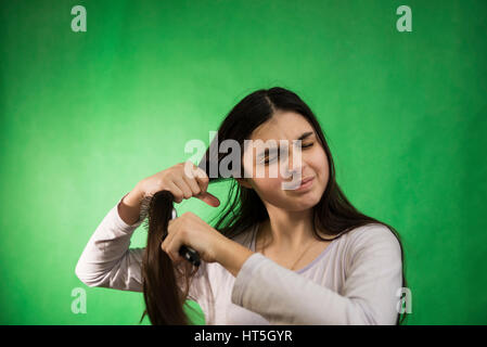 Teen girl in nuisette comb cheveux à fond chroma key vert Banque D'Images