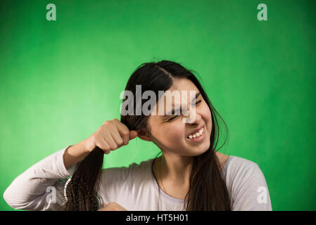 Teen girl in nuisette comb cheveux à fond chroma key vert Banque D'Images