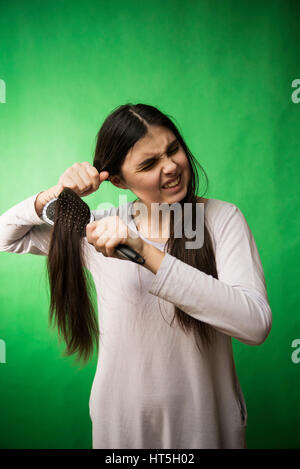 Teen girl in nuisette comb cheveux à fond chroma key vert Banque D'Images