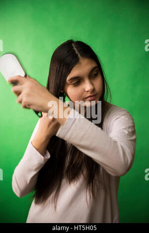 Teen girl in nuisette comb cheveux à fond chroma key vert Banque D'Images