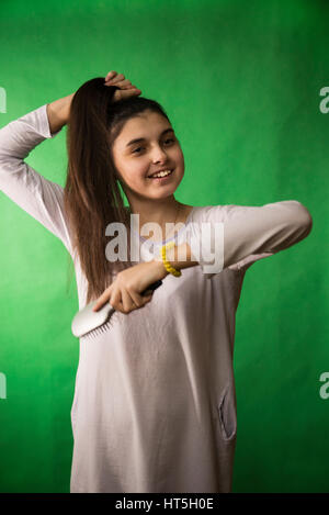 Teen girl in nuisette comb cheveux à fond chroma key vert Banque D'Images