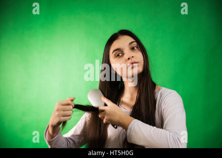 Teen girl in nuisette comb cheveux à fond chroma key vert Banque D'Images