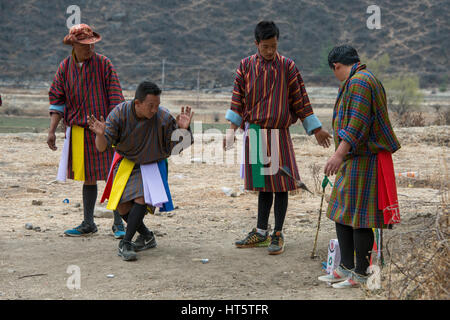 Le Bhoutan, Paro. Khuru (fléchettes) Bhoutanais traditionnel sport de lancer de grandes fléchettes à l'extérieur. Joueurs en tenue traditionnelle faisant une danse quand quelqu'hi Banque D'Images