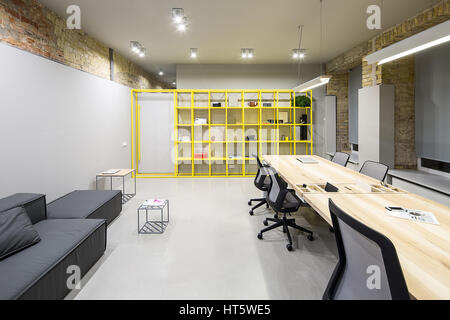 En Bureau de style loft avec des murs en brique et gris. Il y a des lampes en cristal, brillant avec oreiller canapé, tables en bois avec des chaises, des petites tables en métal, métal y Banque D'Images