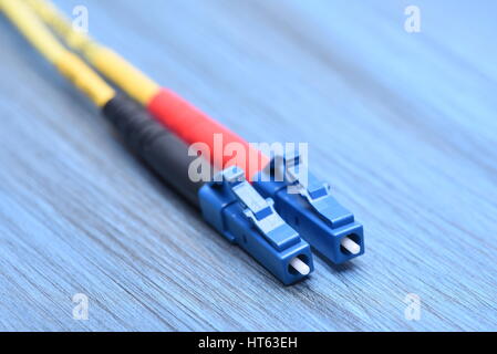 Close up de câbles à fibre optique en mode simple avec bouchon de type LC sur fond bleu Banque D'Images
