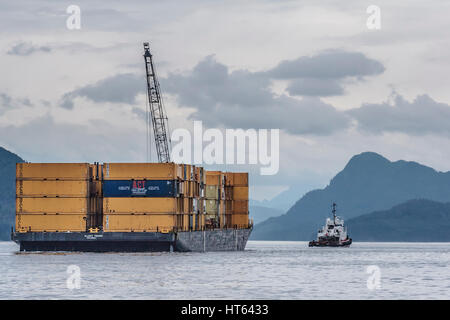 Un remorqueur tire un chaland chargé de conteneurs et équipé d'un tall crane le long du détroit de Johnstone, une partie de la Colombie-Britannique est le passage de l'intérieur. Banque D'Images