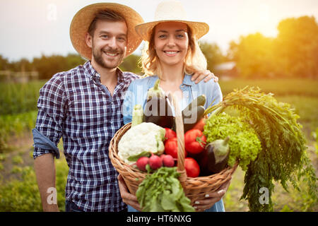 Les agriculteurs Nice couple posing avec panier de légumes dans la nature Banque D'Images