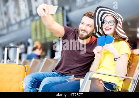 Young happy couple photo selfies avec téléphone en attendant hall de l'aéroport pendant leurs vacances d'été Banque D'Images