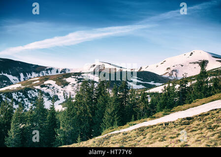 Paysage de montagne avec de la neige de printemps et des forêts de sapin. Nuages spectaculaires couchés sur l'horizon et le soleil brille. Piscine naturelle en arrière-plan de voyage retr Banque D'Images