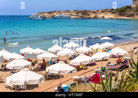 PAPHOS, Chypre - 24 juillet 2016 : les touristes, des chaises longues et des parasols sur chaude journée d'été à Coral Bay Beach. Banque D'Images