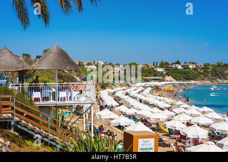 PAPHOS, Chypre - 24 juillet 2016 : les touristes, chaises longues et parasols à la plage de Coral Bay. Banque D'Images