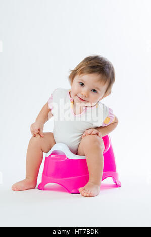 Little smiling girl sitting on un pot. Isolé sur fond blanc. Banque D'Images