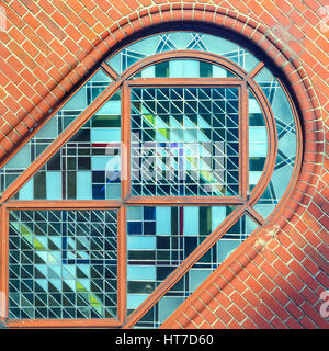 Une partie des vitraux fenêtre cintrée en mur de briques. Close-up photo rogné dans d'scuare Banque D'Images