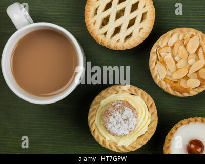 Sélection de gâteaux individuels ou des tartelettes avec une tasse de thé sur un fond vert Banque D'Images