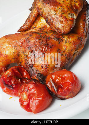 Délicieux poulet frit, tomates rôties sur une plaque blanche Banque D'Images