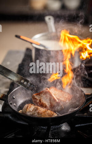 Restaurant Chef cuisinier en cuisine avec poêle, cuisinière faire flambe Banque D'Images
