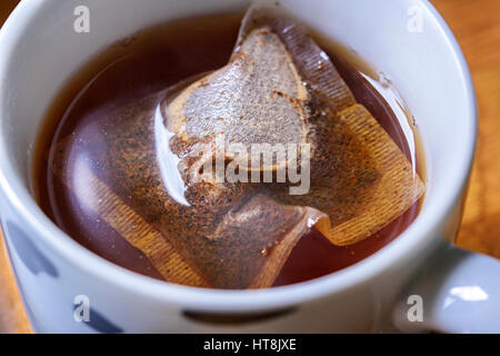 Tasse de thé petit déjeuner anglais traditionnel. Image montre un sachet à thé infuser dans une tasse d'eau bouillante. Flottant sur la surface Banque D'Images