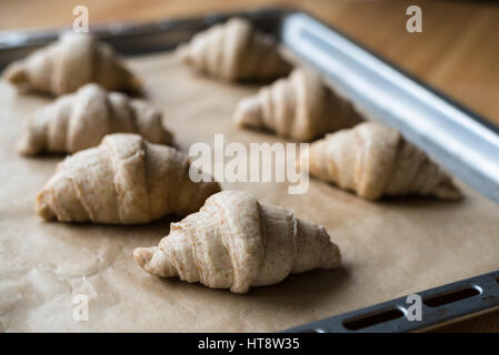 Pas de grains entiers crus boulangerie croissants sur un plat à four avec du papier sulfurisé Banque D'Images