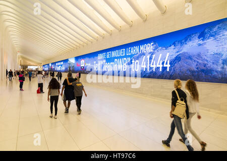 Les gens qui marchent le long de grands panneaux d'affichage LED de la publicité à l'Oculus WTC centre de transports de hall de l'ouest de la ville de New York Banque D'Images