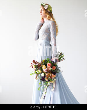 Spring beauty portrait d'une jeune mariée avec une couronne et un bouquet dans la main isolé sur un fond gris. Banque D'Images