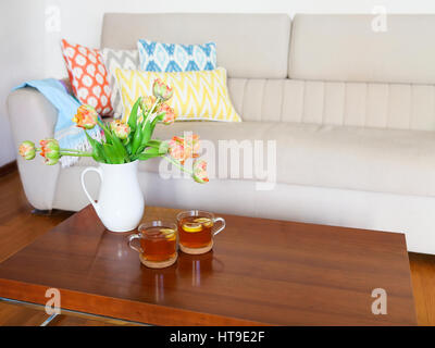 Beau bouquet de tulipes orange avec deux tasses de thé sur la table en bois dans le salon Banque D'Images